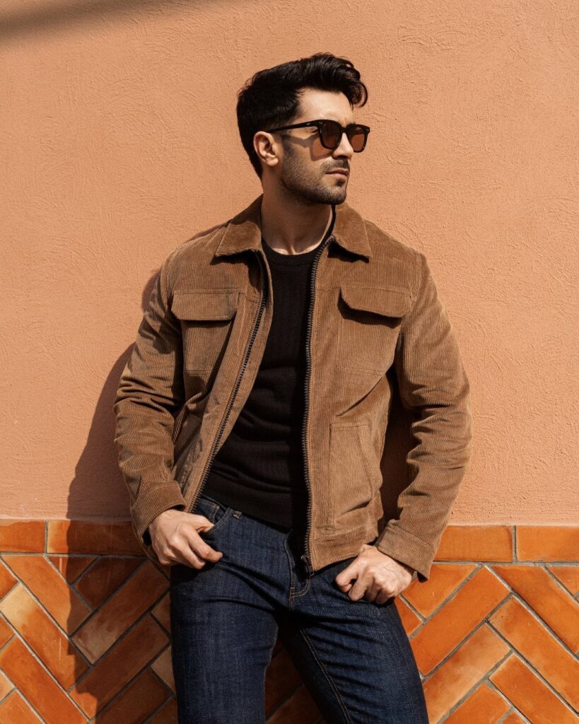 Man wearing a brown corduroy jacket, black shirt, and dark blue jeans.