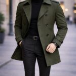 Man wearing an olive green trench coat with a black turtleneck and trousers.