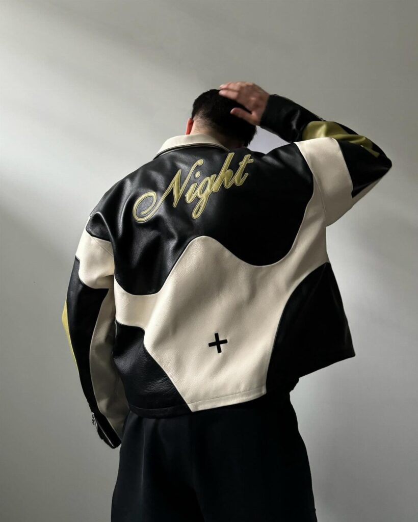 Oversized black and cream leather jacket with gold Night text on the back.