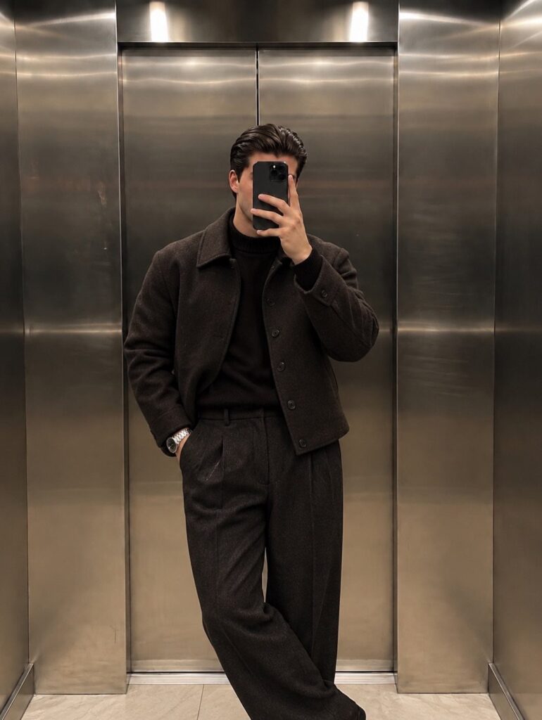 Man in a dark brown wool coat and trousers posing in an elevator