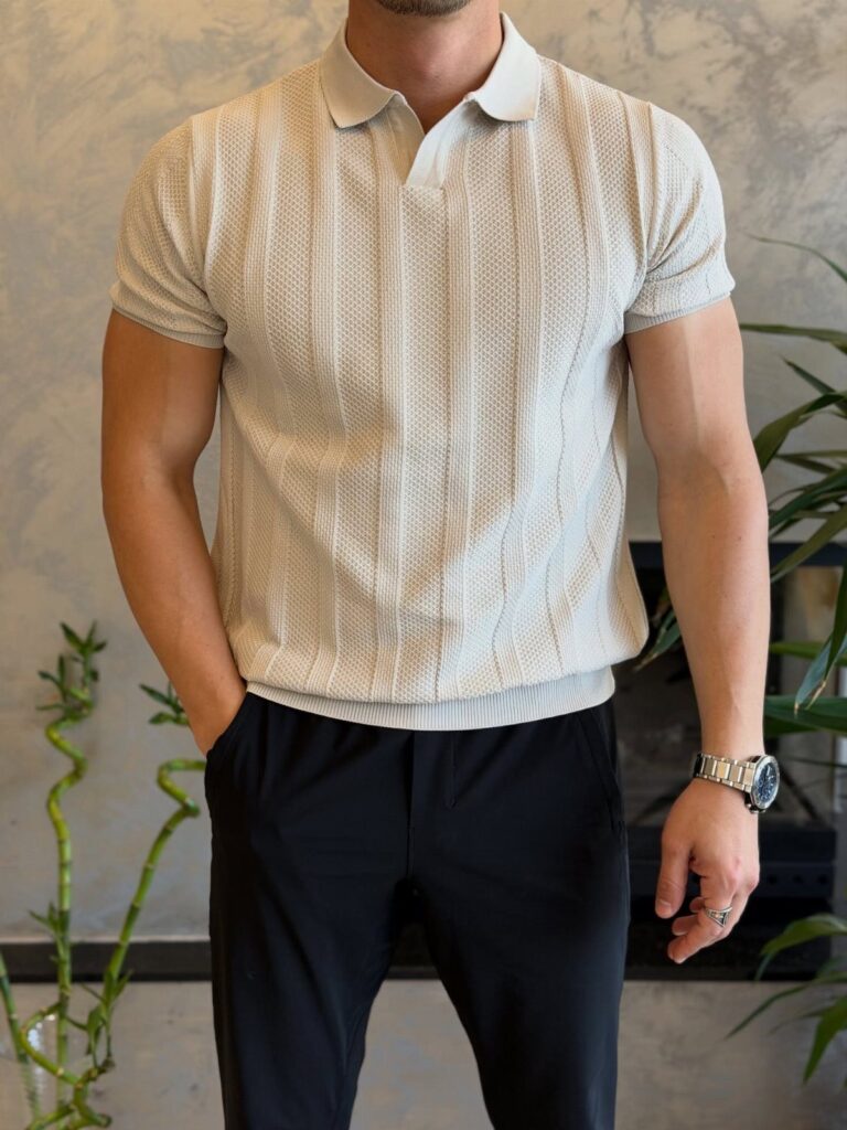 Man wearing a cream textured knit polo shirt and black tailored trousers.