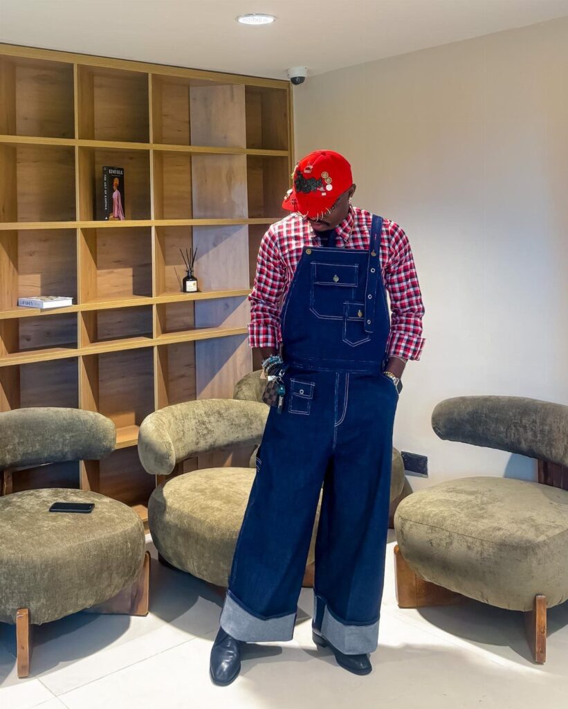 Person wearing dark blue denim overalls over a red checkered button-up shirt and cap.